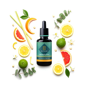 Bottle of Rithim Citrus Fresh Beard Oil surrounded by citrus fruits and leaves on a white background